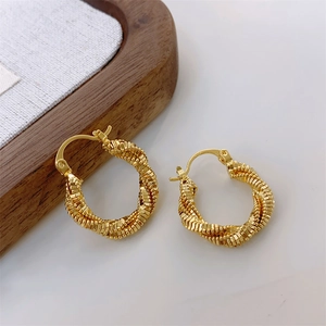 Close-up of golden double-layer twisted rope hoop earrings with hinged closure