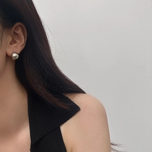 Macro detail of polished silver ball stud earring showing metallic mirror finish