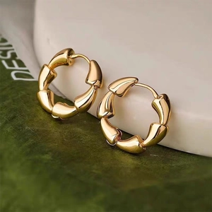 Detailed view of gold hoop earrings with natural bamboo texture on marble stand