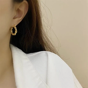 Elegant gold double twisted rope hoop earrings worn by model on a neutral background