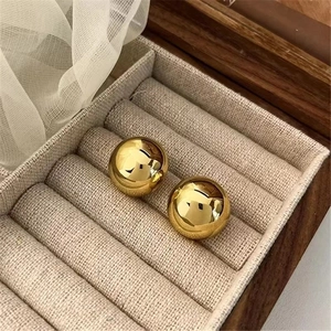 Detailed view of polished gold dome earrings in a wooden jewelry box with soft white lace