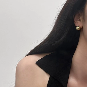 Minimalist golden spherical stud earrings with polished finish on model view