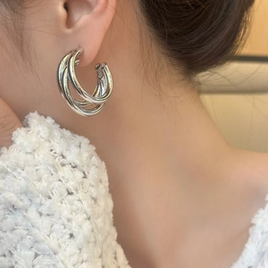 Boucles d'oreilles créoles triples argentées avec fini miroir sur un mannequin femme