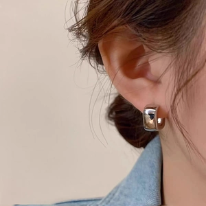 Macro shot of silver C-shaped geometric hoop earrings with a polished mirror finish