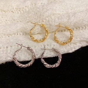 Twisted rope gold and silver hoop earrings with sparkling texture on knit fabric