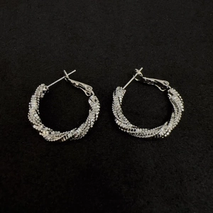 Macro shot of silver twisted hoop earrings with detailed spiral texture on black felt