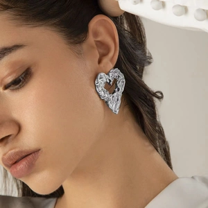 Modern silver liquid lava heart earrings with irregular textured surface on model