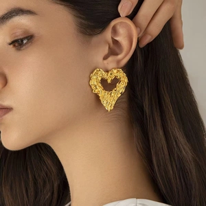 Gold-plated 18K molten lava heart earrings with irregular textured finish on model