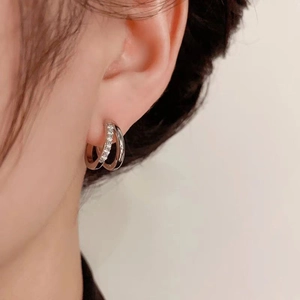 Double layered silver hoop earrings featuring crossed bands and sparkling zircon inlay