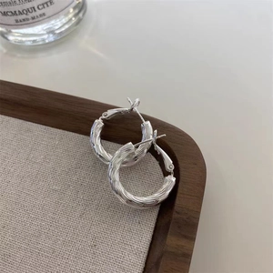 Détail de créoles en argent avec texture métallique torsadée et fermoir de sécurité