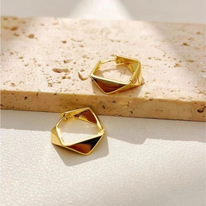 Minimalist geometric gold earrings with hexagon facets and polished metallic finish