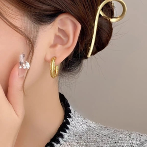 Golden double hoop textured C-shaped earrings worn by a model in a trendy style
