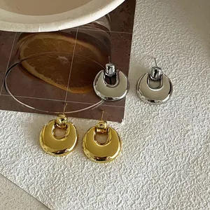 Close-up of polished gold and silver oval earrings on an artistic textured surface
