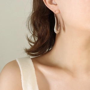 Boucles d'oreilles goutte d'eau en argent poli portées par un modèle au style minimaliste
