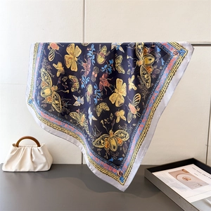 Detailed close-up of blue silk scarf featuring artistic butterfly and insect prints