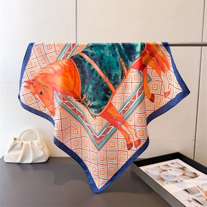 Détail d'un foulard carré en soie avec motif de cheval orange et bordure géométrique