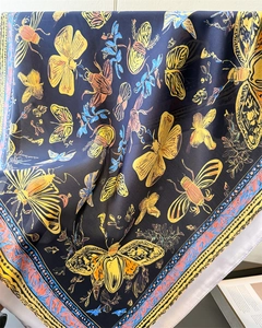 Detail of silk-like scarf featuring blue base with yellow butterfly and insect prints