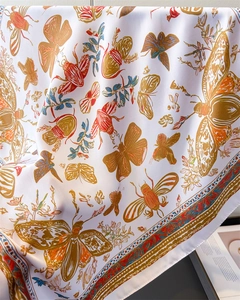 Detail of silk-like scarf featuring intricate butterfly and beetle prints on white fabric