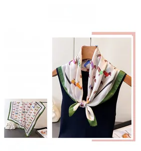 Vue détaillée du foulard en soie crème avec imprimé teckel et bordure verte sur haut noir