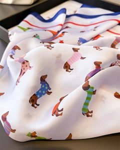 Détail d'un foulard en soie avec imprimé teckel et bords élégants rouge et bleu