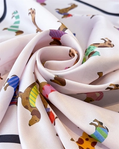 Détail d'un foulard en soie rose avec imprimés teckel et texture satinée douce pliée en spirale