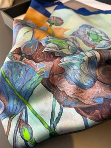 Detailed close-up of artistic lotus print on smooth silk scarf with blue edge