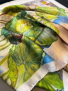 Detailed view of lightweight silk scarf featuring artistic green lotus leaf patterns