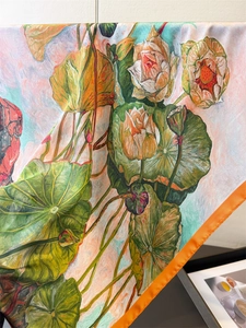 Detailed view of artistic lotus print on premium silk scarf with orange satin edges