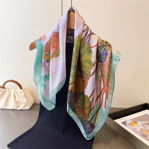 Elegant lotus leaf print faux silk square scarf draped on a wooden hanger with a stylish bag