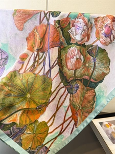 Detail of artistic lotus print silk scarf with light blue satin rolled edges and soft texture