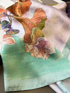 Detailed close-up of floral oil painting pattern and rolled edge on luxury silk scarf