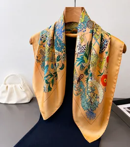 Dettaglio di un foulard in seta arancione caldo con stampe di uccelli e motivi leopardati