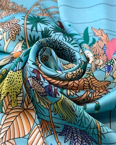 Dettaglio macro della stampa floreale tropicale su foulard in raso blu setoso