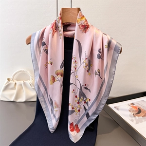 Pink silk-feel square scarf with floral prints and grey border on a wooden hanger