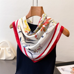 Close-up of elegant floral print silk scarf with red border on a wooden hanger