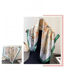 Detail of silk square scarf showing intricate orange floral print and dark green hem edge