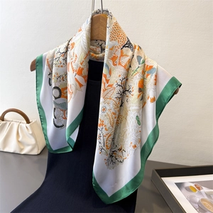 Detail of silk-like scarf with nature patterns on a wooden hanger with a white handbag