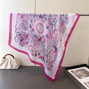 Detailed shot of floral silk square scarf draped on a metal stand with a stylish handbag