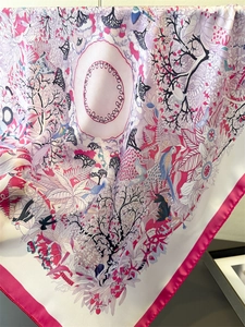 Detailed close-up of silk-textured scarf showing intricate bird and floral illustrations