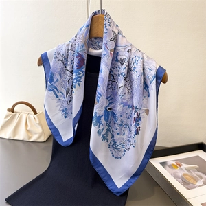 Elegant floral print silk scarf with bird pattern and navy blue border on display