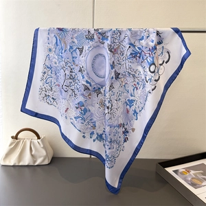 Detailed view of large satin silk scarf with blue nature prints and rolled edges