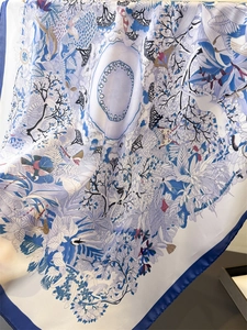 Close-up of bird and floral prints on elegant blue and white silk scarf edge