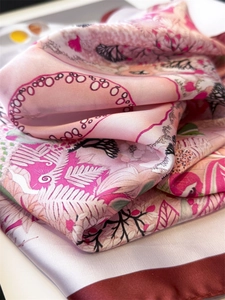 Close-up of pink silk scarf texture with floral prints and elegant red rolled edges