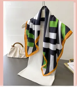 Close-up of geometric color block silk scarf with orange hem styled on white top