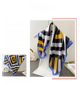 Detail of silk-like scarf with geometric yellow and black stripes and navy blue edges