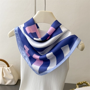 Elegant geometric striped silk-like square scarf in navy and pink displayed on a vest