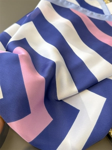 Detail of striped silk-like scarf with blue white and pink geometric wave patterns