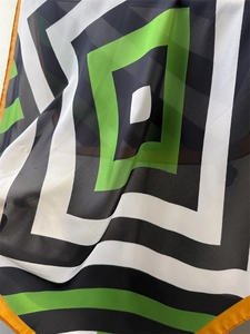 Macro detail of geometric silk scarf fabric with black, green and white abstract patterns