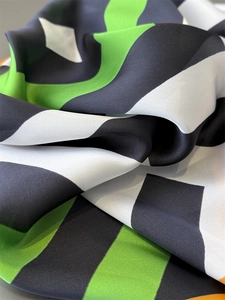 Close-up of green and black striped silk scarf with elegant satin luster and texture