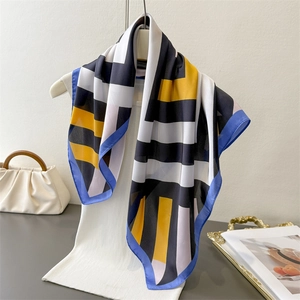 Detail of silk-like scarf with geometric stripes and blue rolled edges on a mannequin